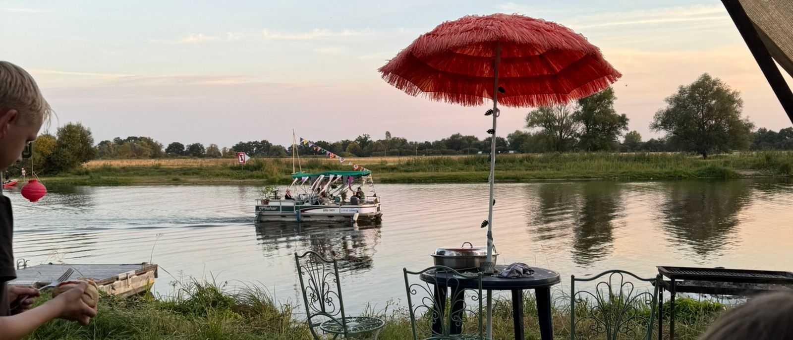Geschmücktes Boot Kati auf der Havel, im Vordergrund Garten mit rotem Schirm und Grill an der Weinbergstraße