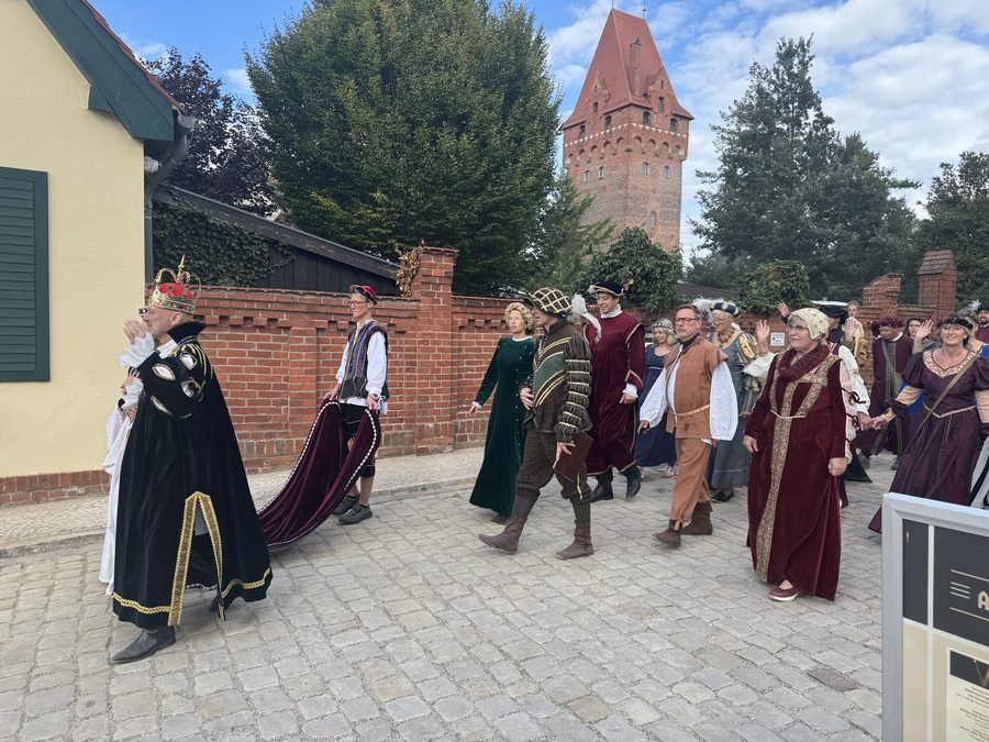 Gefolge in historischen Gewändern auf dem Weg zur Burg