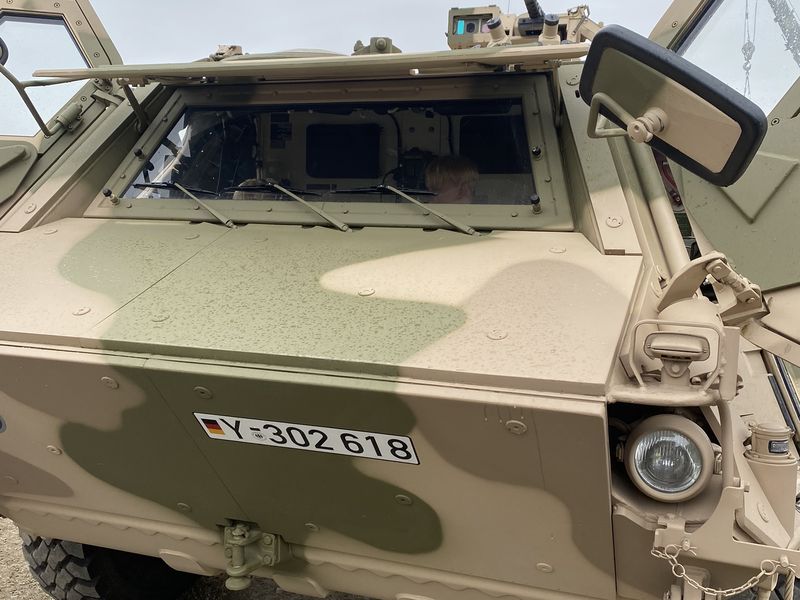 Child in the driver’s seat of a sand-coloured protected vehicle with open doors