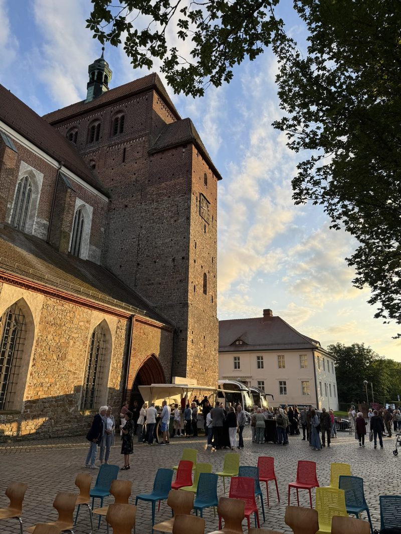 Abendlicht am Domturm, bunte Stühle und Gäste vor dem Westportal