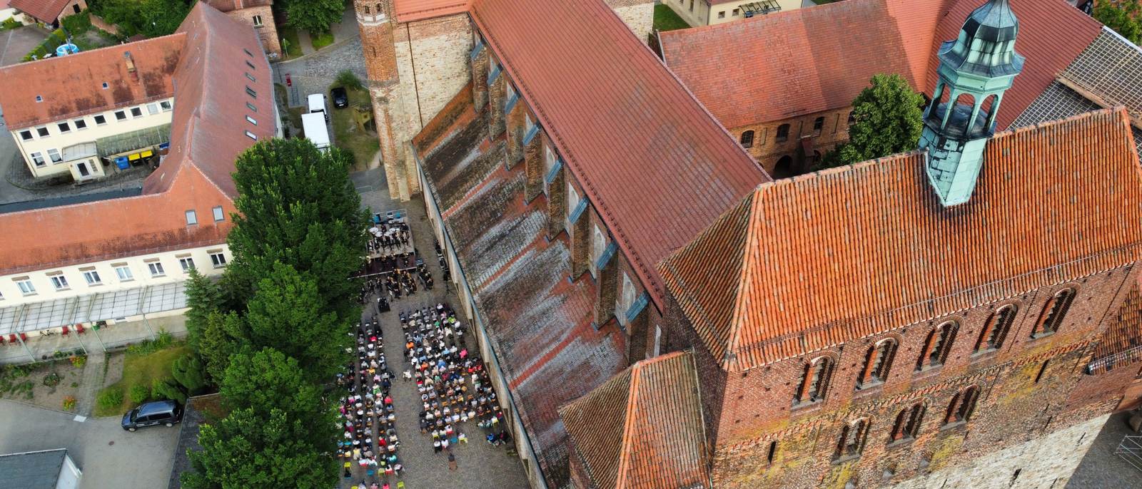 Luftbild: Sommerkonzert im Hof am Havelberger Dom, Orchester und Publikum zwischen Kirche und Klostergebäuden