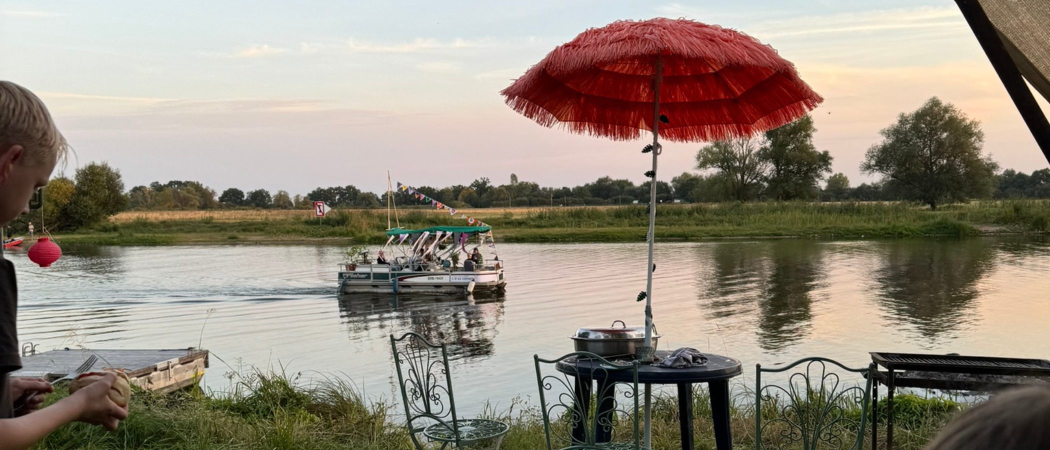 Blick von einem Garten an der Weinbergstraße auf die Havel mit geschmücktem Boot