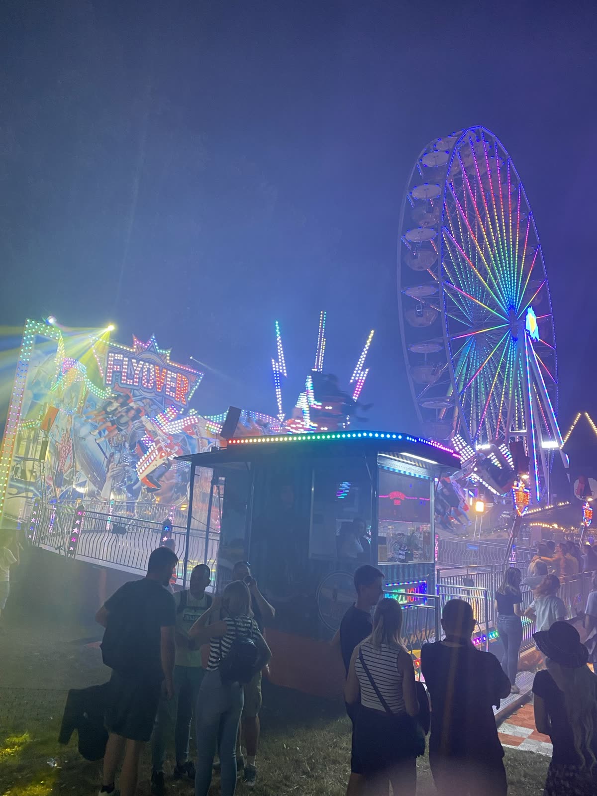 Fahrgeschäft FLYOVER und Riesenrad bei Nacht