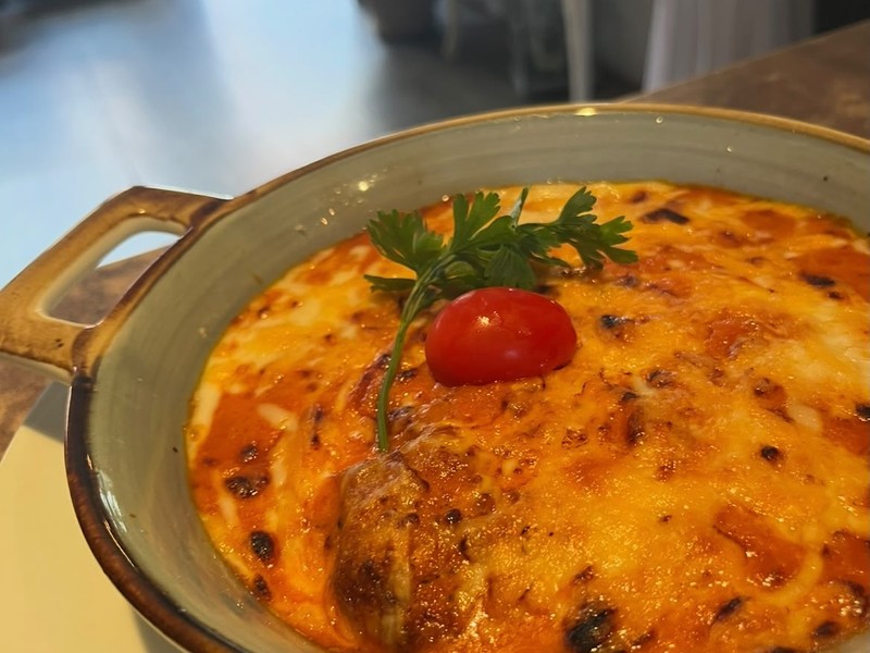 Überbackenes Gericht mit Käsekruste und Kirschtomate