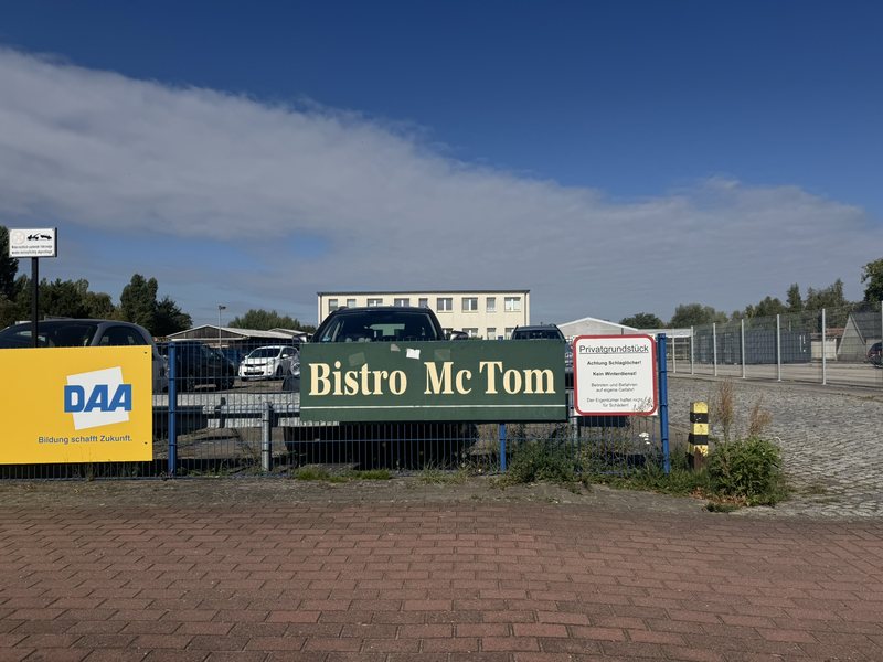 Einfahrt mit Schild Bistro McTom