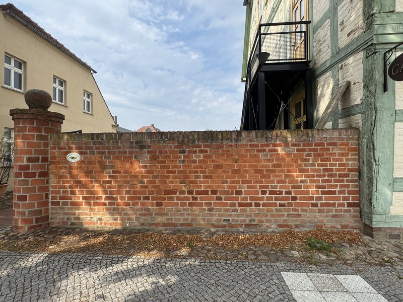 Ziegelmauer mit eingravierten Namen an der Domkurie Domherrnstraße 8