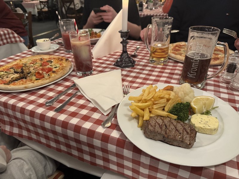 Tischszene mit Steak, Pizza und Bier bei Mezza Luna